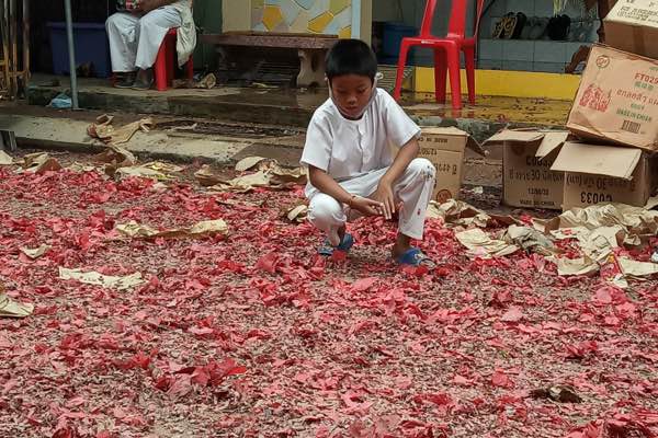 young boy among the remains of firecrackers after the vegetarian festival